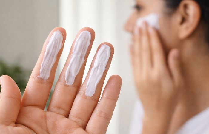 Applying sunscreen using the three finger rule for correct SPF 50 coverage on face