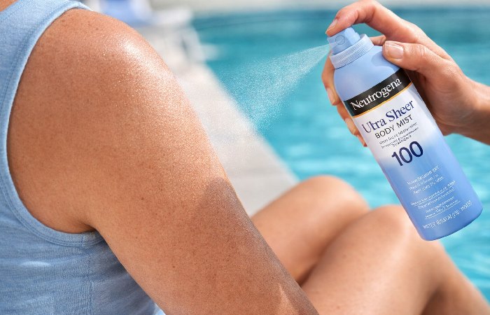 Person applying Neutrogena sunscreen outdoors near beach setting for water-resistant sun protection
