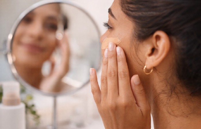 Person applying tinted sunscreen to face as part of morning skincare routine